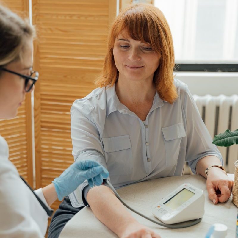 Doctor checking a patient's blood pressure using a digital monitor during a routine checkup.