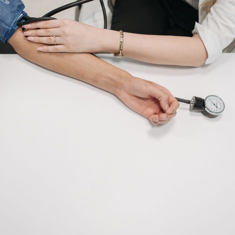 A medical practitioner checking a patient's blood pressure in a clinical setting.